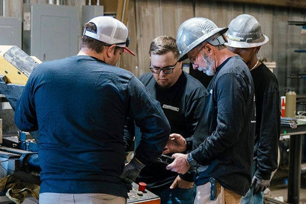 values-extra-mile Construction team evaluating rebar installation techniques while using jobsite equipment and concrete forming accessories.