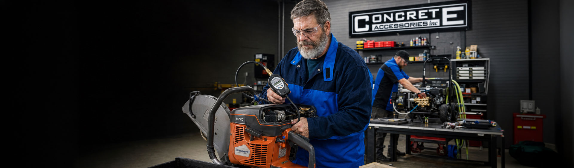 Technician inspecting concrete cutting equipment in a workshop, showcasing essential jobsite tools and maintenance practices.